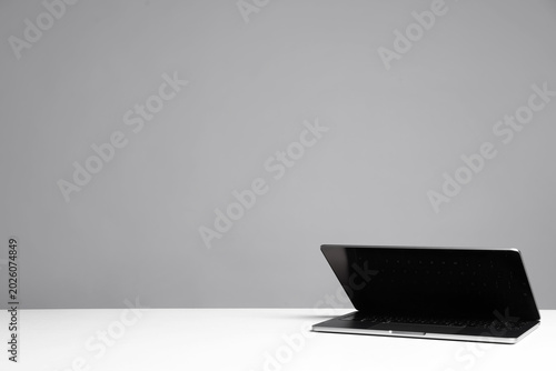 Stylish workplace. Modern laptop on white table against gray background. Space for text