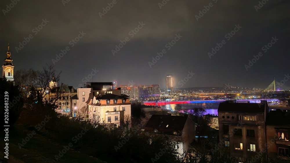 Fototapeta premium Aerial view of a city at sunset seen from a window, with buildings stretching into the distance. Warm golden light illuminating the urban skyline.