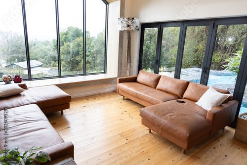 Fotografie Tan leather sofa chaise sitting on wood floor by windows, phone resting, lamp st