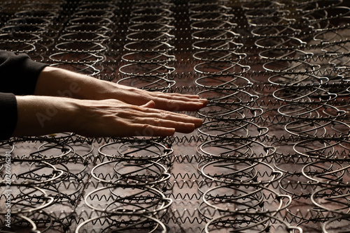 Foto Women's hands check the firmness of mattress springs before repairing or replaci