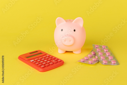 Cost Analysis in Healthcare: Piggy Bank, Calculator, and Medicine on Yellow Background