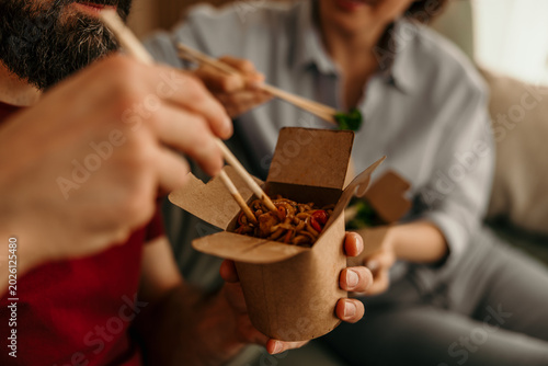 Bild auf Leinwand Couple eating takeout noodles with chopsticks at home