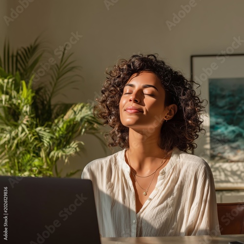 Serene woman enjoying sunlight and a mindful moment at her laptop
