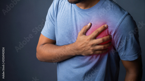 Young man suffering from severe chest pain and heart attack, clutching his chest with hand on red highlighted area, concept of cardiology, medical emergency, and health problems.