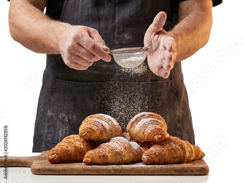 Chef dusting fresh croissants with icing sugar, transparent background