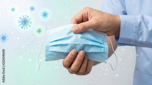 Hands holding blue surgical face mask.