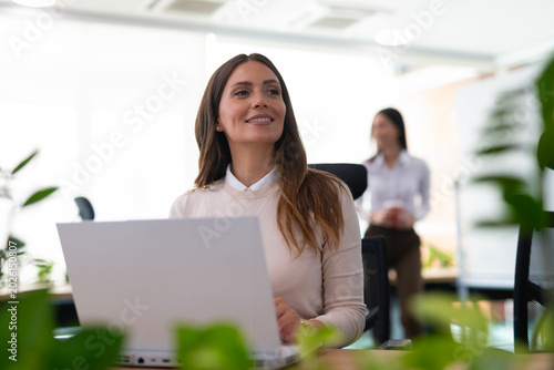 Professional woman smiling looking away with laptop in office