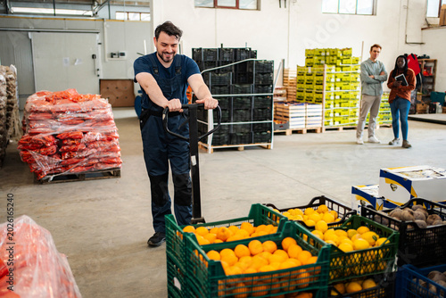 Fotografie Male worker moving fresh fruit crates in warehouse