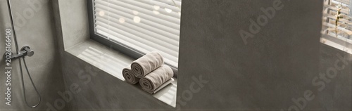 Rolled towels on window sill in concrete shower alcove