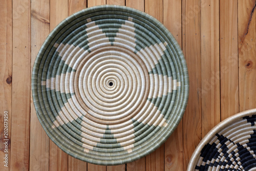 Traditional handwoven Agaseke basket bowl with sunburst pattern displayed on a wooden surface in Kigali, Rwanda