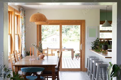 Bright dining room area with a sliding patio door, modern metal bar stools, and a wooden dining table