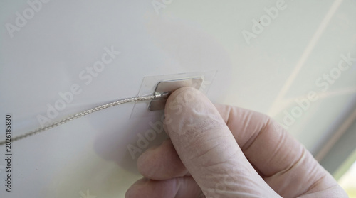 A hand wearing a nitrile glove installs the temperature sensor on the back panel of the solar module