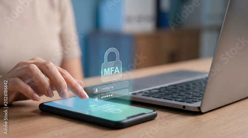 Woman using smartphone with laptop on wooden desk for secure online authentication