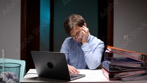 Photos Overworked man experiencing fatigue and burnout, leaning on his hand while sitti