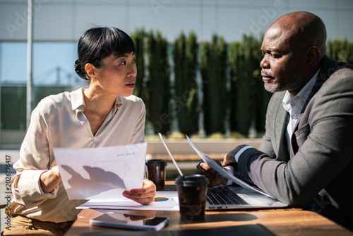 Two business professionals discussing reports outside an office