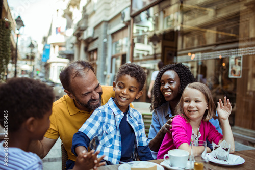 Parents and children laughing at outdoor city cafe