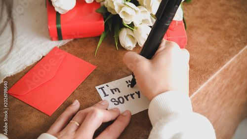 Tableau sur toile Woman’s hand writing “I’m Sorry” on paper