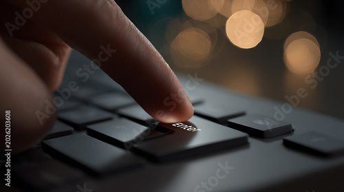 Close-up of a human finger pressing the glowing 'Enter' key on a dark computer keyboard, with blurred bokeh lights in the background, symbolizing action and commitment in modern technology