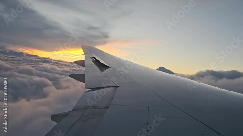 An airplane wing above the clouds at dawn on a flight to Buenos Aires. The plane enters the cloud layer during landing.
