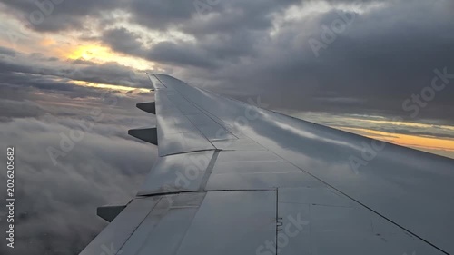 An airplane wing above the clouds at dawn on a flight to Buenos Aires. The plane flies through the clouds during landing.
