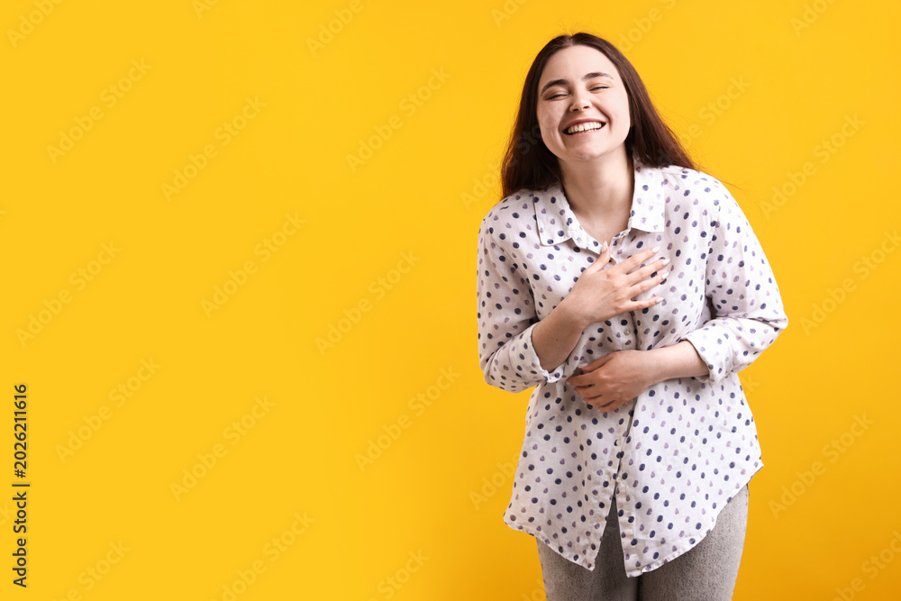 Obraz premium Happy woman laughing at joke on yellow background, space for text