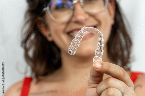 Canvastavla Woman holding transparent aligner for teeth straightening, smiling with braces already on