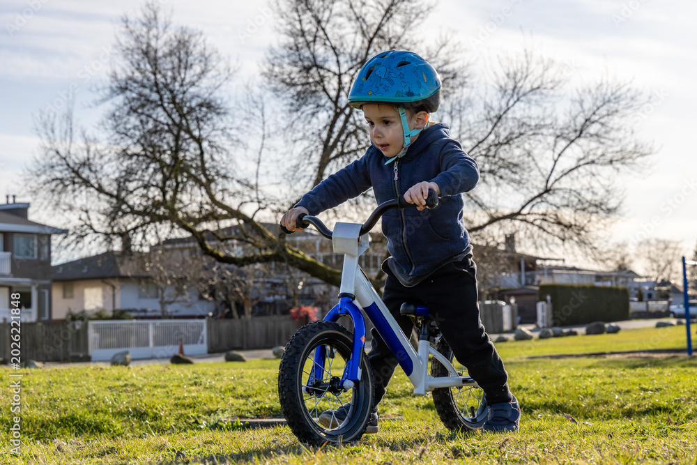 Obraz premium Young Boy Learning To Ride A Bike With Helmet In A Park In Burnaby Vancouver BC
