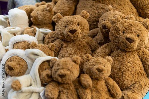 A large group of brown fluffy teddy bears piled together on display.
