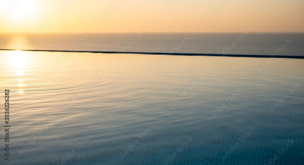 Obraz premium Ocean sunrise with smooth ripple reflections and horizon light streaks for travel, branding backgrounds, and inspirational marketing design