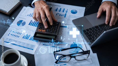 Businessman analyzing healthcare investment data using calculator and laptop, financial planning