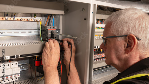 Quadro su tela Senior electrical engineer using a multi meter to test a power isolation switch on a building management system