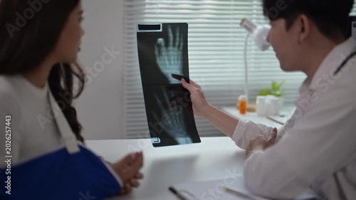Medical Consultation with Doctor Showing Hand X-ray to Patient in Clinic Setting