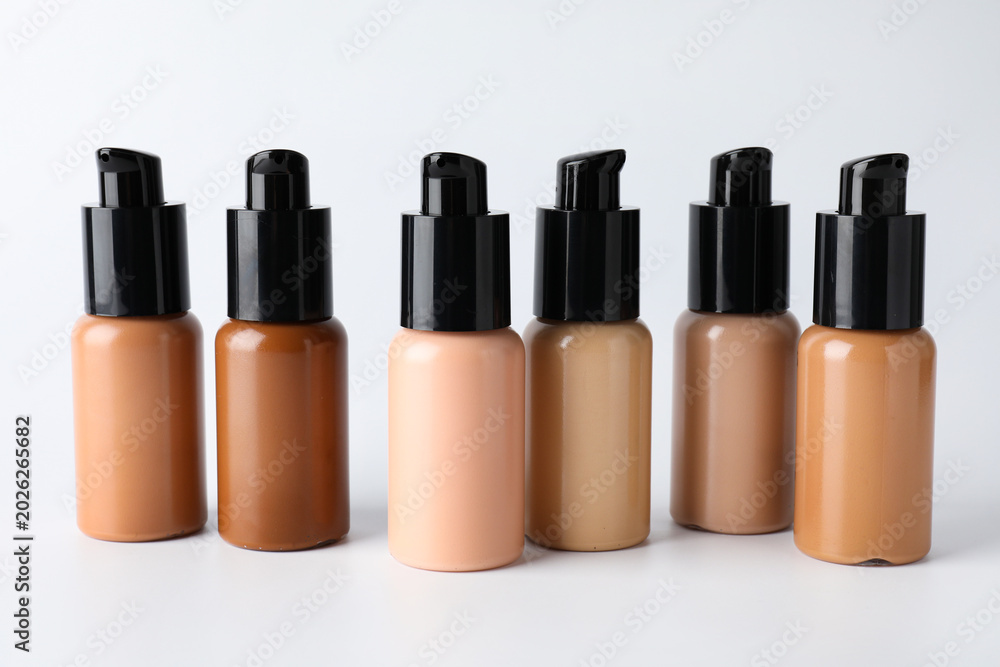 Obraz premium Bottles of skin foundations in different shades on light grey background, closeup