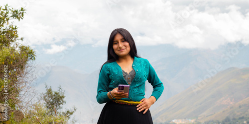 Konstfotografi Mujer campesina atractiva en América Latina, feliz mientras usa un teléfono inteligente mirada a un espacio  publicidad y aislada en un fondo naturaleza