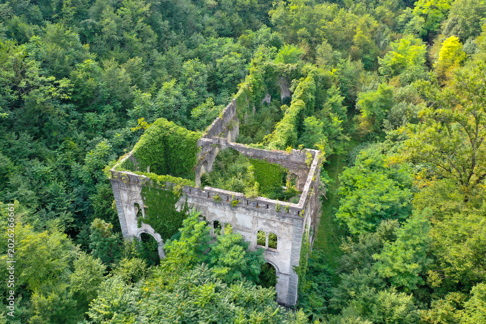 Ταπετσαρία Aerial drone view of the abandoned Ex Centrale Idroelettrica Rovereto power plant ruins surrounded by dense forest near Rovereto, Italy