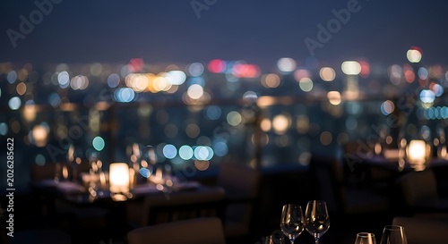 Elegant restaurant tables with wine glasses and candles with a blurred city skyline background at night