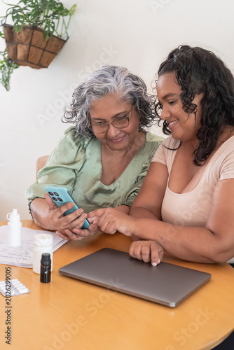 Adult daughter assisting senior mother with smartphone healthcare