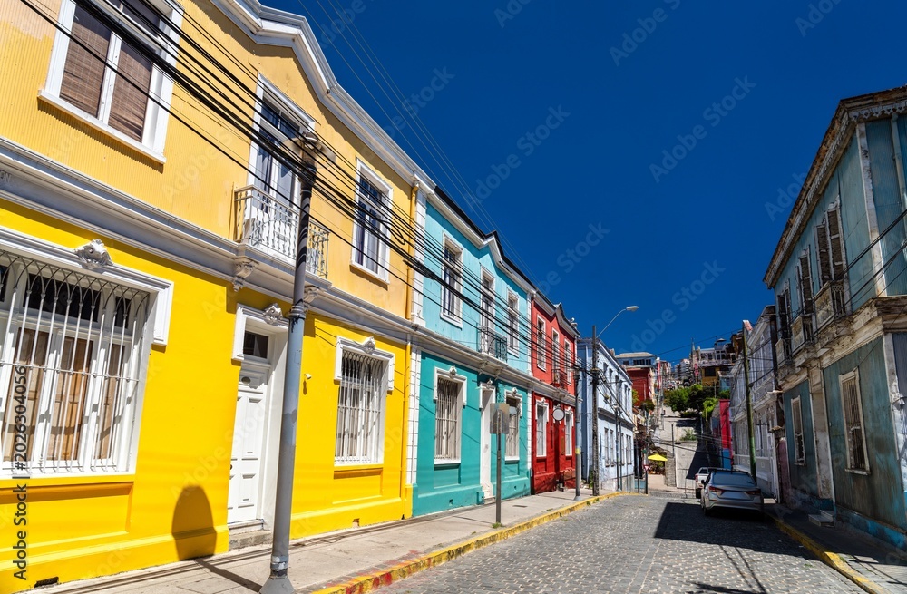 Fototapeta premium View of Templeman Street in between Cerro Concepcion and Cerro Alegre. Colorful historic houses line the steep cobblestone street under a deep blue sky