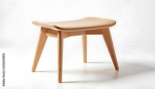 A wooden stool with a curved seat and four tapered legs sits on a plain white floor in a brightly lit room with a subtle shadow.
