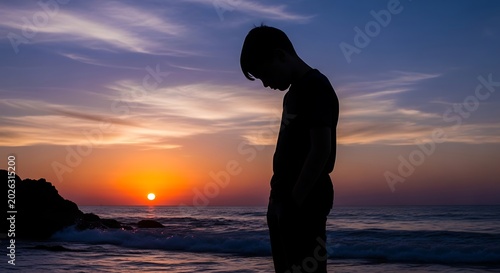 Solitary child's silhouette at sunset by the ocean