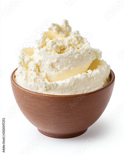 Creamy cottage cheese mound piled high in a textured brown ceramic bowl isolated on white
