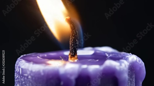 Close up of a lit purple candle flame against a black background