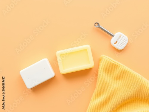 Natural bar soap with white container and yellow towel. Minimalist bath hygiene products on orange background. Organic skincare flat lay.