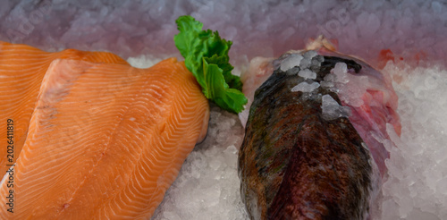 rohes orangerotes Lachsfilet und ganzer Speisefisch auf Eis in der Frischetheke