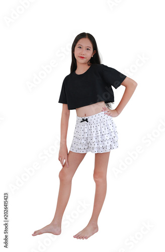 Portrait of young Asian girl strikes confident pose, wearing a black crop top and a tiered polka-dot skirt against white background.
