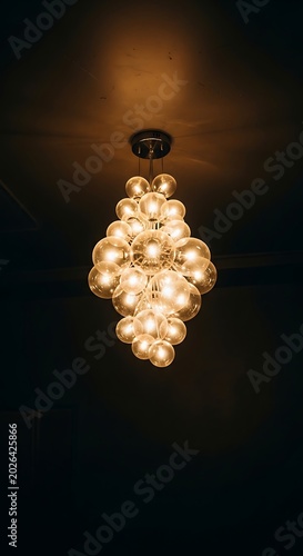 Illuminated cascading orb chandelier indoors with warm glow
