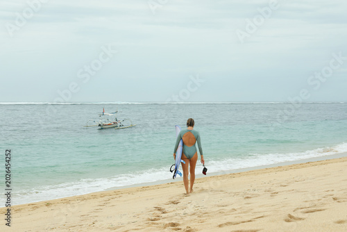 Bild auf Leinwand Person walks along the beach carrying snorkeling gear