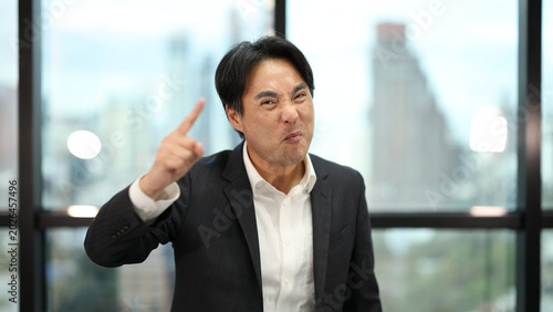 Tableau sur toile Expressive Asian Businessman Pointing Finger with Determined Facial Expression i