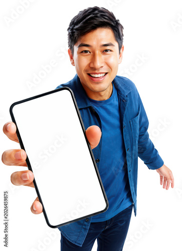Man Showing a Smartphone: A cheerful young Asian man in a blue shirt and jeans holds a smartphone with a blank screen forward, inviting viewers to explore its features.