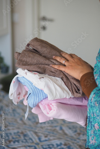 Photography Holding a stack of clean clothes in a room